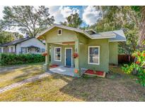 Charming green bungalow featuring a covered porch and beautifully landscaped front yard at 112 S Chandler Ave, Deland, FL 32724