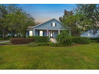 Attractive light blue house with a porch, landscaping, and American flag at 450 W Delaware Ave, Lake Helen, FL 32744