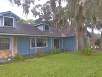 Charming home featuring light blue siding, stone accents, dormer windows and a lush green lawn at 573 Pelican Bay Dr, Daytona Beach, FL 32119