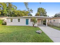 Charming single-story home featuring a well-manicured lawn, a bright blue front door, and a convenient carport at 522 Powers Ave, Port Orange, FL 32127