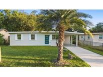 Charming single-story home featuring a well-maintained lawn, a vibrant blue door, and a covered parking area at 522 Powers Ave, Port Orange, FL 32127