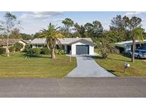 Charming single-story home with a well-manicured lawn, palm tree, and attached garage at 1437 Colin Kelly Ave, Daytona Beach, FL 32124