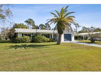 Charming single-story home featuring a well-manicured lawn, mature palm tree, and attached garage, offering curb appeal at 1437 Colin Kelly Ave, Daytona Beach, FL 32124