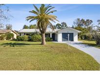 Charming single-story home with a well-manicured lawn, mature palm tree, and a blue two-car garage door at 1437 Colin Kelly Ave, Daytona Beach, FL 32124
