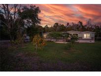 Charming home exterior featuring a spacious yard and colorful orange tree at sunset at 227 N Putnam Grove Rd, Oak Hill, FL 32759