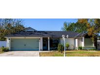 One-story house featuring a light green garage door, a gray roof, and well-manicured lawn at 1083 E Normandy Blvd, Deltona, FL 32725
