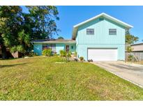 Light teal house with a white garage door and well-maintained lawn at 453 Merrimac Dr, Port Orange, FL 32127