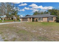 Brick home with a large yard, driveway, and basketball hoop at 1945 Eden Dr, Deltona, FL 32725