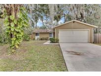 Tan single-story house with attached garage and mature landscaping at 2125 Queen Palm Dr, Edgewater, FL 32141