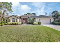 Charming single-story home with a well-manicured lawn, inviting red door, and attached two-car garage at 376 Hampton Hills Ct, Debary, FL 32713