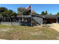 Gray brick ranch house with a 2-car garage and American flag at 444 S Deerwood Ave, Orlando, FL 32825