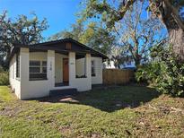 Charming bungalow with white brick facade, orange door, and fenced yard at 610 Division St, Daytona Beach, FL 32114