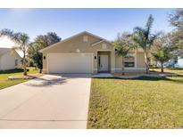 Tan one-story house with a two-car garage and palm trees at 981 Wilmington Dr, Deltona, FL 32725