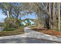 Two-story teal home with long driveway, surrounded by mature trees and Spanish moss at 10480 Se 101St Avenue Rd, Belleview, FL 34420