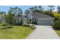 Gray two-story house with a three-car garage and a well-manicured lawn at 2423 Wild Turkey Creek Ln, Port Orange, FL 32128