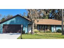 Charming single-story home with blue siding, stone accents, a brown roof, and a well-maintained lawn at 487 Dawnview Sq, Port Orange, FL 32127