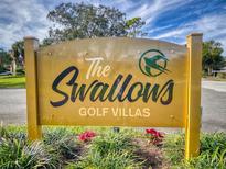 The Swallows Golf Villas entrance sign with vibrant flowers, blue sky, and wispy clouds at 55 Fairway Dr # 3D, Debary, FL 32713
