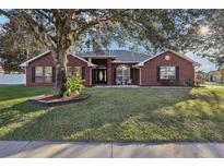 Brick home with a landscaped lawn and mature trees at 601 Autumn Fern Ln, Deland, FL 32720