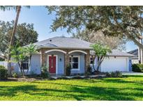 Single-story home with stone accents, red door, and landscaped lawn at 12 Peruvian Ln, Ormond Beach, FL 32174