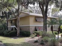Tan two-story building with brown roof and shutters, nestled among lush greenery at 130 Jasmine Woods Ct # 15C, Deltona, FL 32725