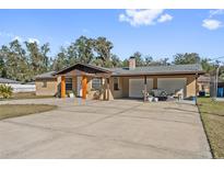 Tan single-story house with attached carport and large driveway at 1701 N Stone St, Deland, FL 32720