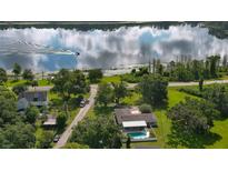 Aerial view of a home with pool, lakefront access, and lush landscaping at 2530 E New York Ave, Deland, FL 32724