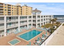 Oceanfront building with pool, patio furniture, and beach access at 3509 S Atlantic Ave # 208, New Smyrna Beach, FL 32169