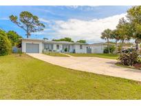 Ranch-style home with a large driveway and nicely landscaped lawn at 469 S Halifax Dr, Ormond Beach, FL 32176