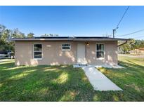 Tan single story house with a walkway, lawn, and solar panels on the roof at 501 W Lisbon Pkwy, Deland, FL 32720