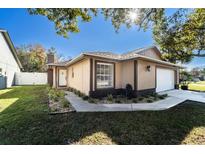 Tan house with white garage door, landscaped lawn, and walkway at 1413 La Paloma Cir, Winter Springs, FL 32708