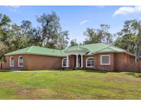 Brick house with green metal roof, large yard, and walkway at 1908 S Farm Rd, Deland, FL 32720
