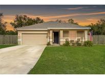 Beige house with a two-car garage and a well-manicured lawn at 304 Gardenia Ave, Debary, FL 32713