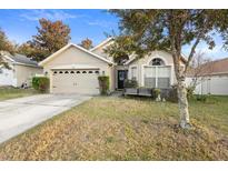 Tan house with a two-car garage and a well-maintained lawn at 3125 Wood Rose Way, Deltona, FL 32725