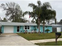 Charming light blue house with a well-manicured lawn and palm trees at 744 Baywood Ln, South Daytona, FL 32119