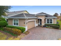 Tan single-story house with a paved driveway and lush landscaping at 1105 Gardenshire Ln, Deland, FL 32724