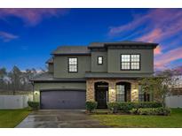 Two-story house with stone accents and a dark-colored garage door at 1106 Woods Landing Dr, Minneola, FL 34715