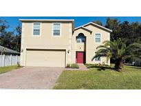 Two-story house with a red door, attached garage, and palm tree in the front yard at 119 No Name Key Dr, Deland, FL 32720