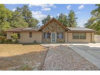 Charming single-story home boasts stone accents, solar panels, and a concrete driveway with decorative gravel walkway at 1240 W Voorhis Ave, Deland, FL 32720