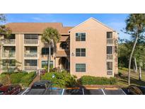 Three-story condo building with tan facade, balconies, palm trees, and convenient parking at 1401 S Palmetto Ave # 614, Daytona Beach, FL 32114