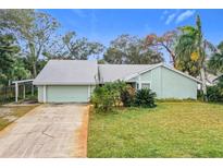 Light teal house with a gray roof, driveway, and lush green lawn at 1412 Oak Forest Dr, Ormond Beach, FL 32174