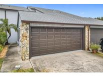 Attached garage with brown door and stone accents at 347 Castlewood Ln, New Smyrna Beach, FL 32168