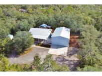A bird's eye view of a charming house with a light-colored roof, a spacious garage, and a lush green surrounding at 4525 Owls Nest Ct, De Leon Springs, FL 32130