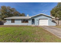 Cute light blue house with a white garage door and well-maintained lawn at 89 Rosewood Ave, Ormond Beach, FL 32174