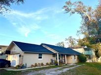 Charming single Gathering home features a long driveway and inviting front porch with mature trees and blue skies overhead at 236 Plaza Oval, Casselberry, FL 32707