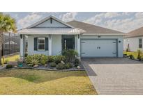 Charming single-story home featuring light blue siding, a two-car garage, and well-manicured landscaping at 105 Cerise Ct, Daytona Beach, FL 32124