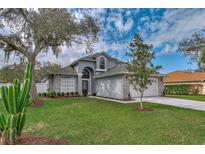 Beautiful two-story home with a well-manicured lawn, mature trees, and a charming exterior at 6150 Half Moon Dr, Port Orange, FL 32127