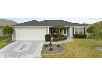 Charming single Gathering home features a well maintained lawn, 2-car garage and decorative driveway at 2879 Crowned Caterpillar Dr, The Villages, FL 32163