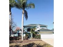 Charming two-story home with a brick driveway, lush landscaping, and beautiful palm trees at 112 Muscovy Ct, Daytona Beach, FL 32119