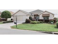 Charming single Gathering home with a manicured lawn, lush landscaping, and a two car garage at 12841 Se 97Th Terrace Rd, Summerfield, FL 34491