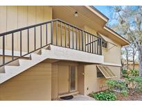 Inviting condo entrance with tan siding, black railings, and well-maintained landscaping at 140 Orchid Woods Ct # 7A, Deltona, FL 32725